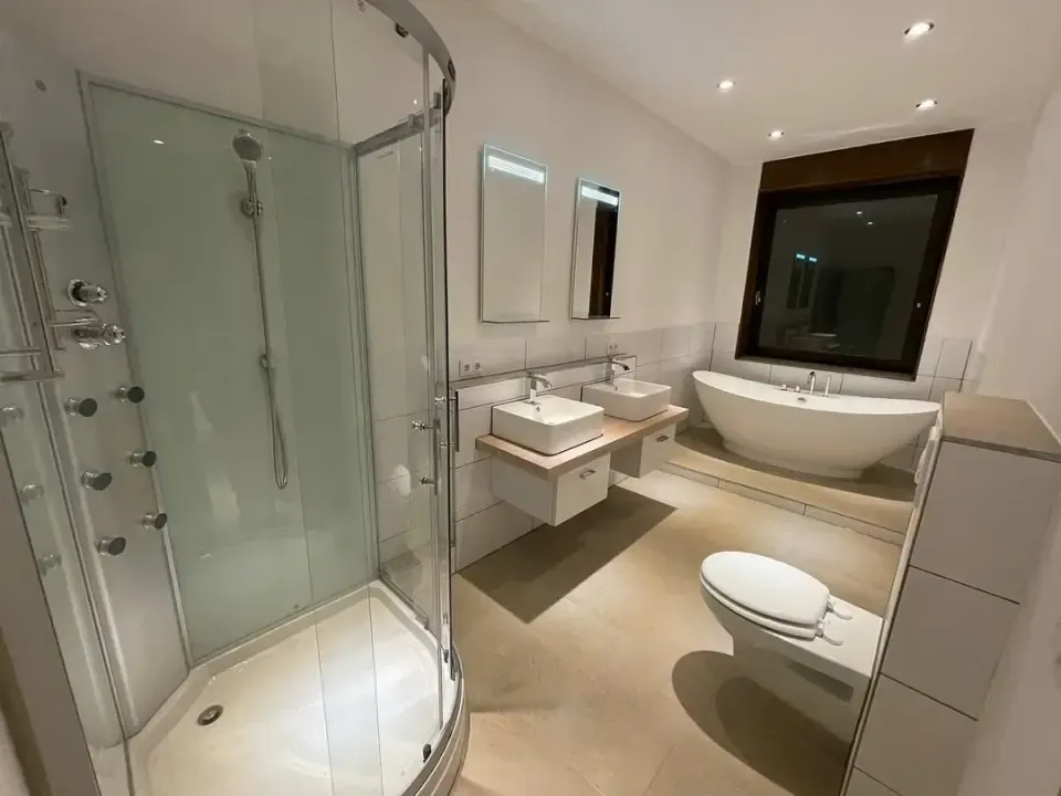 Gefliestes Badezimmer mit Eckdusche, Doppelwaschtisch und freistehender Badewanne
