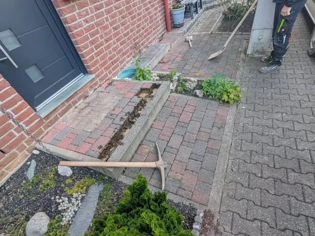 Hauseingang vor der Sanierung mit aufgebrochener Pflasterung und abgesackter Eingangsstufe