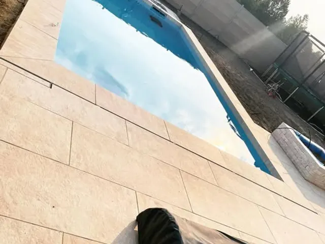 Poolterrasse aus hellen Großformatplatten mit schmalen Fugen rund um ein blaues Becken