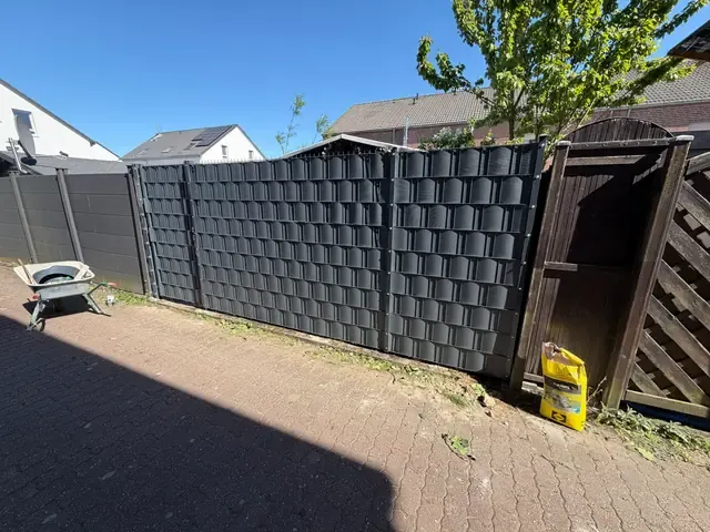 Doppelstabmattenzaun mit anthrazitfarbenem Sichtschutz entlang einer gepflasterten Zufahrt in Viersen-Dülken