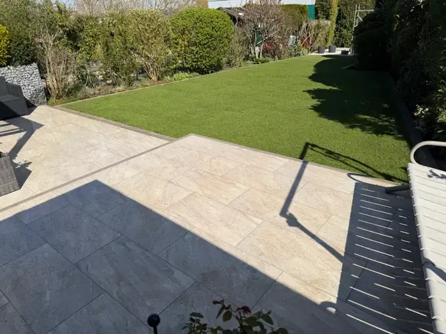 Terrasse aus Großformatplatten mit angrenzender Rasenfläche und Heckeneinfassung in Viersen