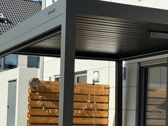 Terrassenüberdachung mit anthrazitfarbenem Lamellendach und Sichtschutzwand aus Holzlamellen
